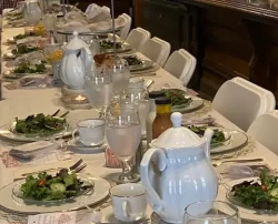 dining table set with salads, tea service, and crystal glasses.