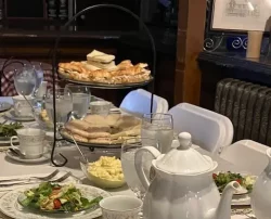 Tea setup with tiered trays of pastries and salads.